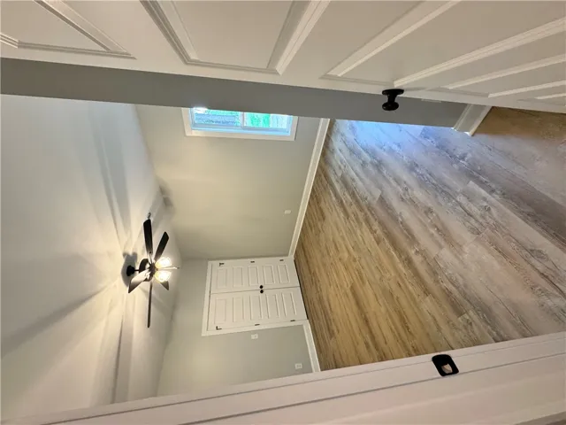 This interior hallway features beautiful wood flooring, a ceiling fan, and abundant natural light.