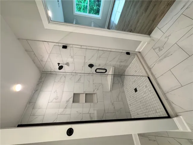This spacious shower features sleek tile and a skylight, perfect for refreshing mornings.