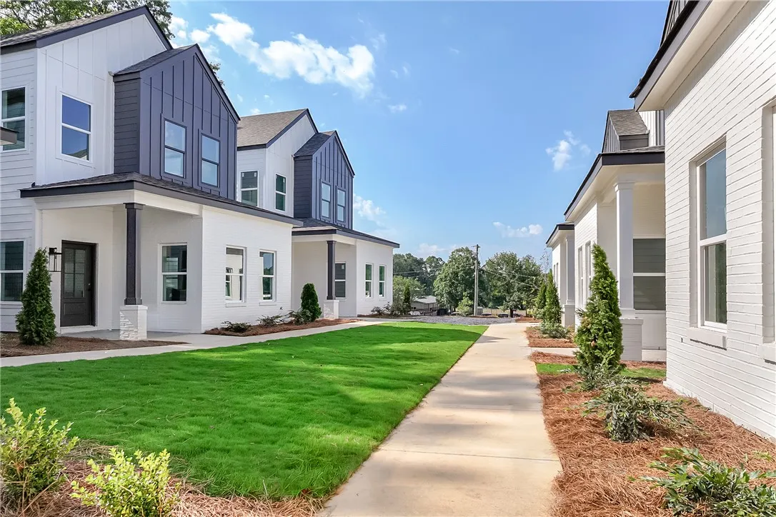 Modern townhomes feature crisp white brick exteriors and manicured lawns, offering a fresh streetscape.