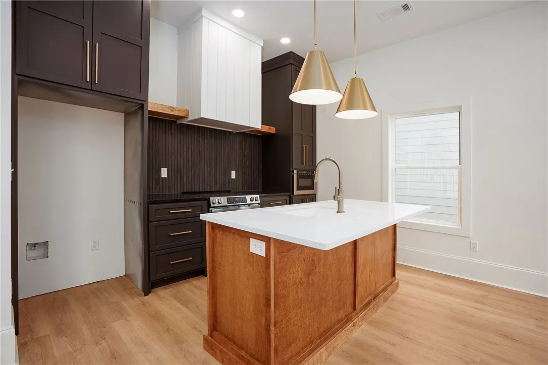 A contemporary kitchen space boasts sleek cabinetry, a substantial island, and modern pendant lighting.