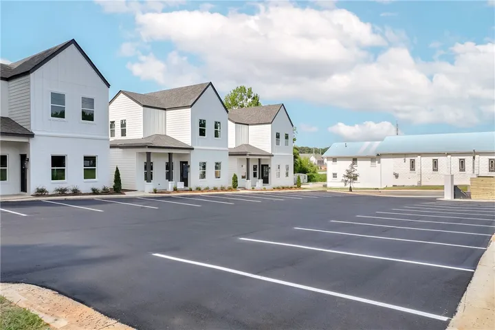 Modern white structures with dark trim and a newly paved parking area offer a contemporary commercial presence.