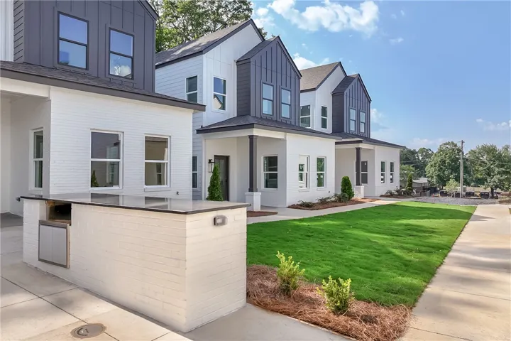 A striking modern exterior features crisp white brick, dark accents, and vibrant green lawns.