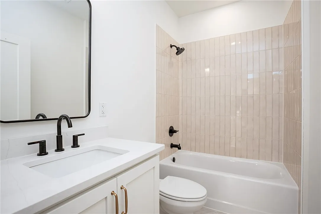 A well-appointed bathroom with contemporary fixtures, featuring a sleek vanity and a tiled shower/tub combo.