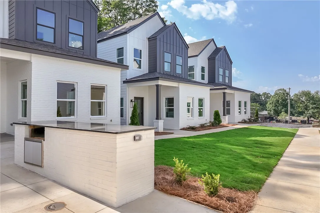 Modern townhomes showcasing crisp white brick and contrasting dark siding, with a neatly manicured lawn.
