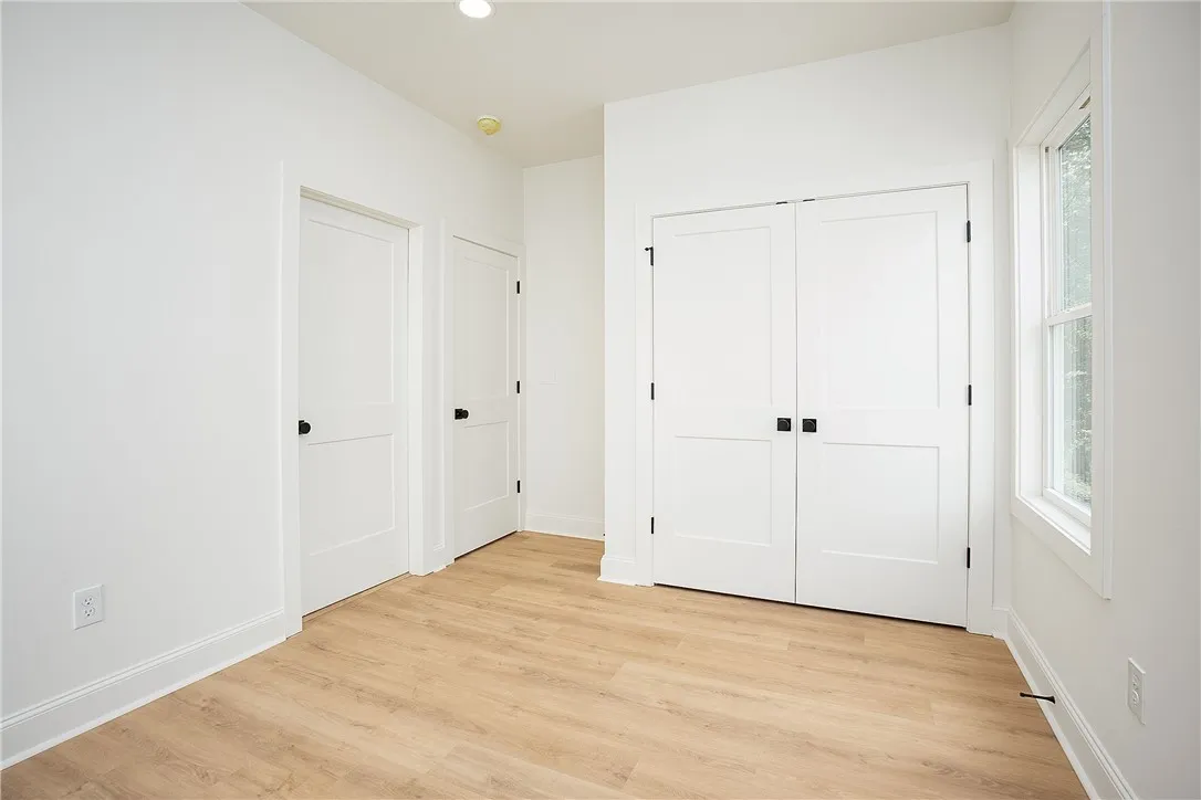 Crisp white interiors with bright windows and warm wood flooring define this inviting bedroom space.