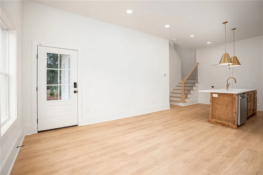 A well-lit main living space, perfect for entertaining, with rich wood flooring and a staircase leading to the upper level.