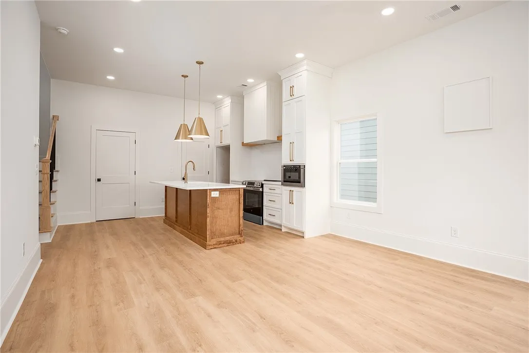 A well-lit, open-concept kitchen and living area featuring a central island and contemporary fixtures.