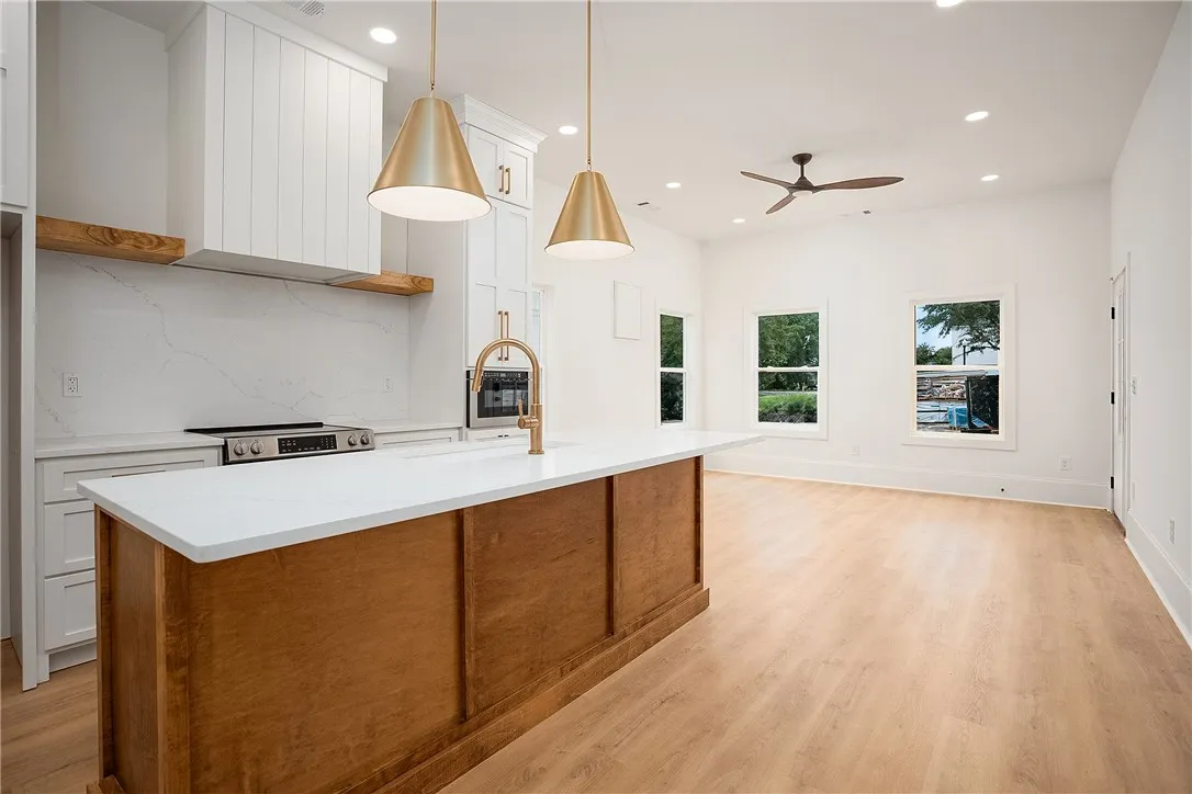 A grand central island anchors this pristine kitchen and living area, complete with sleek modern appliances and golden accents.