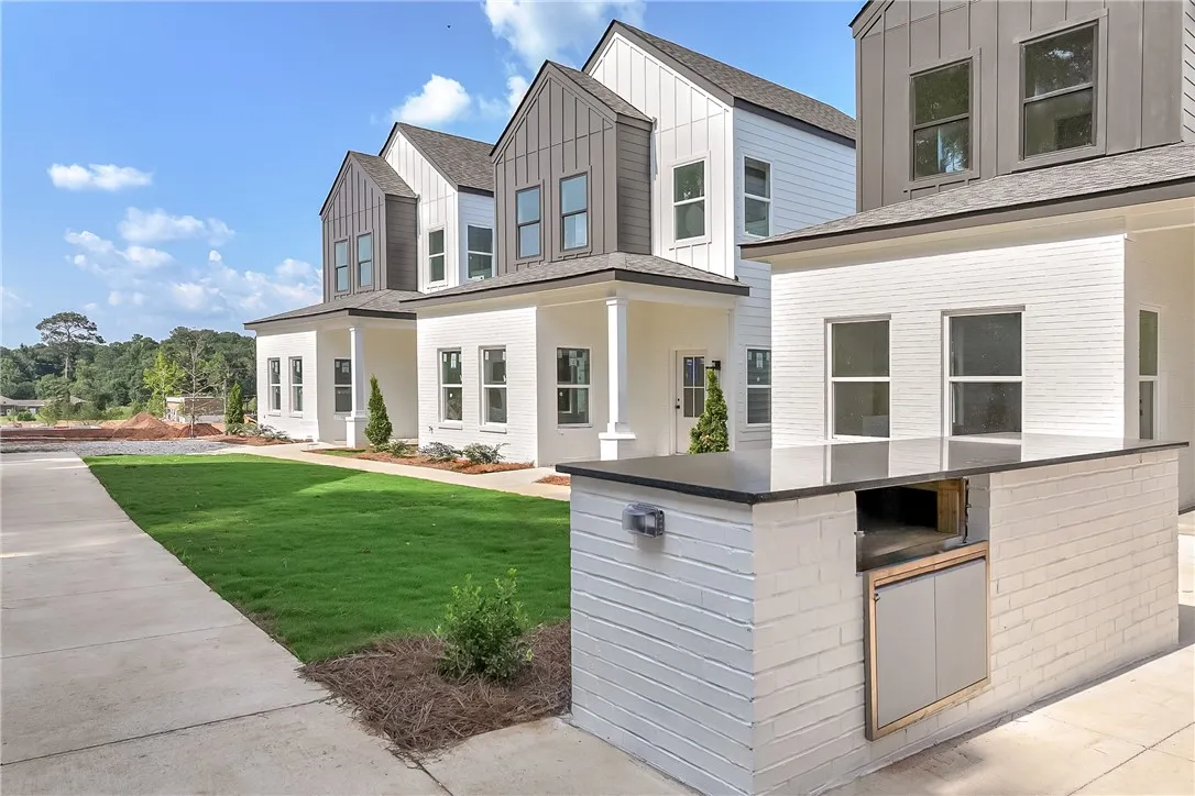 Modern townhomes feature an inviting outdoor kitchen and meticulously maintained lawns.