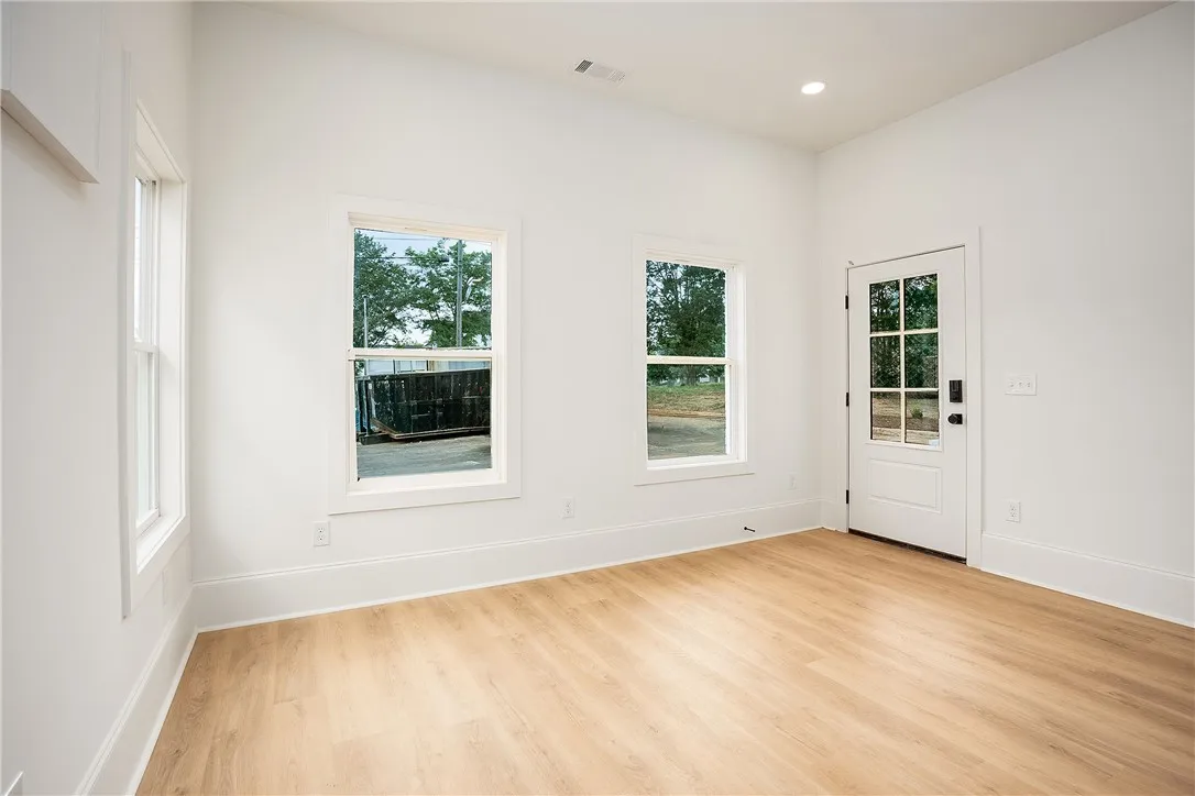Natural light floods this room, highlighting the warm, wide plank flooring and pristine white trim.
