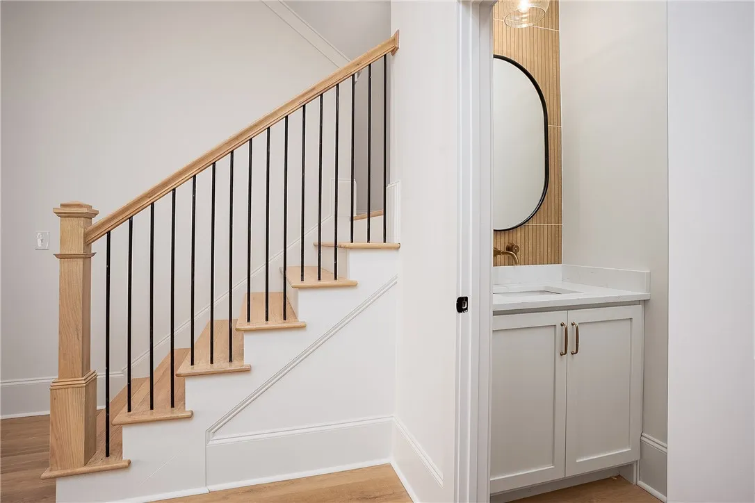 Elegant hardwood stairs with sleek iron balusters create a welcoming entry alongside a conveniently located powder room.