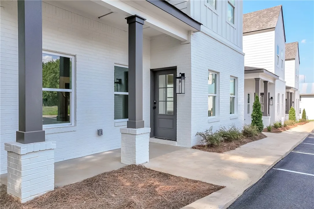 A row of modern white brick townhomes with dark trim and clean landscaping creates an inviting street presence.