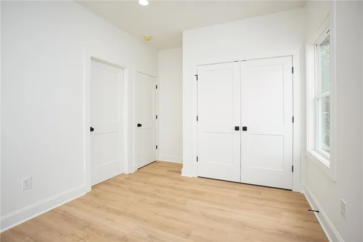 Crisp white interiors with bright windows and warm wood flooring define this inviting bedroom space.