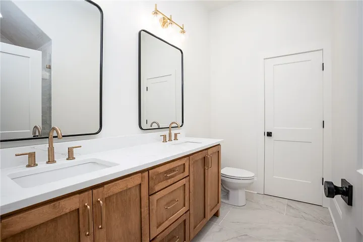 Double vanities with quartz countertops and sleek brass fixtures define this primary bathroom's polished appeal.