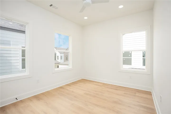 A well-lit room showcasing crisp walls and light-toned hardwood flooring.