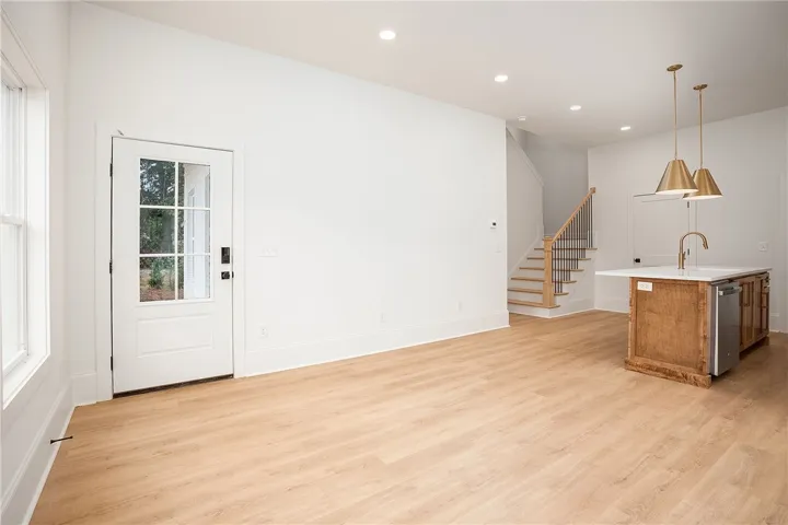 A well-lit main living space, perfect for entertaining, with rich wood flooring and a staircase leading to the upper level.