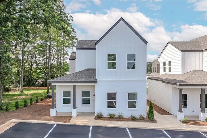 Modern townhome with board and batten siding, nestled among mature trees and offering convenient parking.