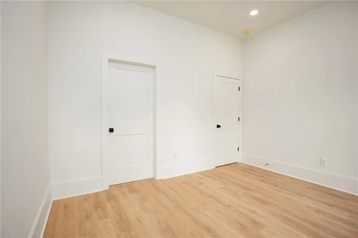 Recessed lighting illuminates this bright room with light-toned flooring and classic white doors.