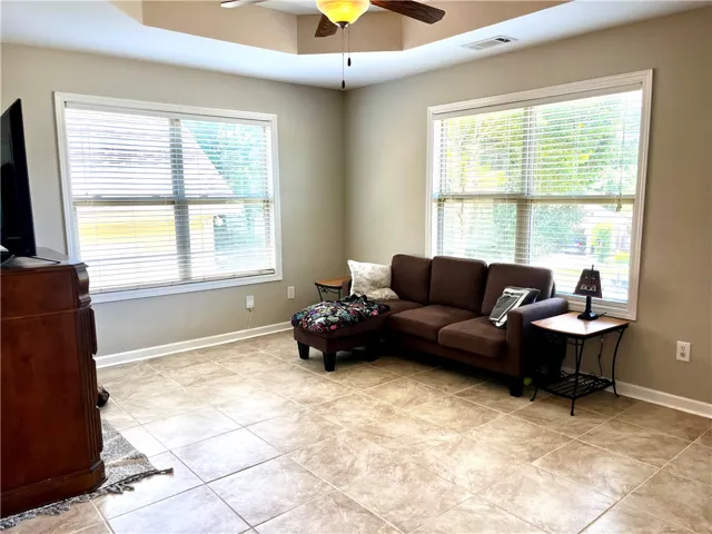A comfortable living space boasts ceramic tile flooring and abundant natural illumination through large windows.