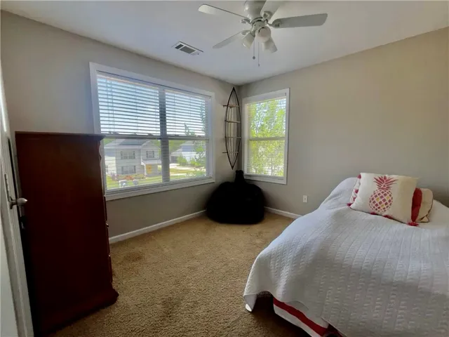 A comfortable bedroom with neighborhood views features soft carpeting and ample natural light.