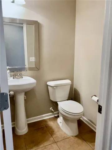 A well-maintained powder room features a classic pedestal sink and practical tile flooring.