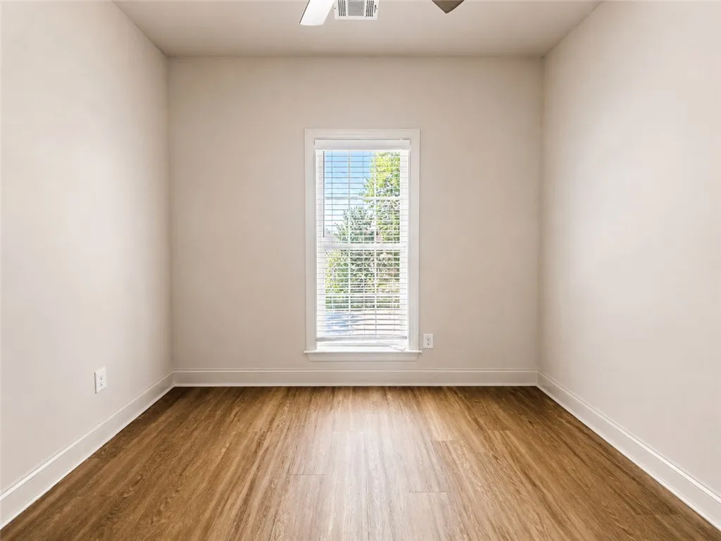 Primary Bedroom Rich wood-inspired flooring and a single window define this versatile space.