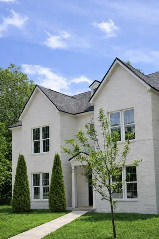 A concrete walkway leads to the entrance of this multi-level home featuring timeless brick construction.