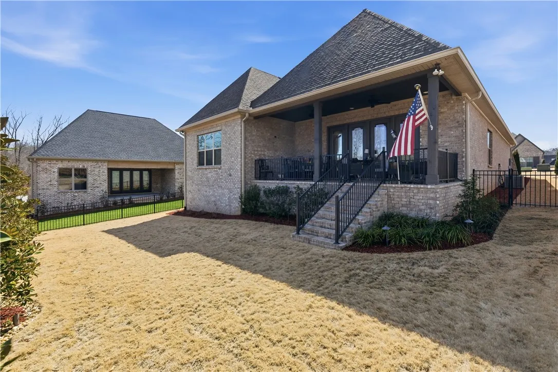 The rear façade is defined by an expansive covered porch and intentional landscape design.