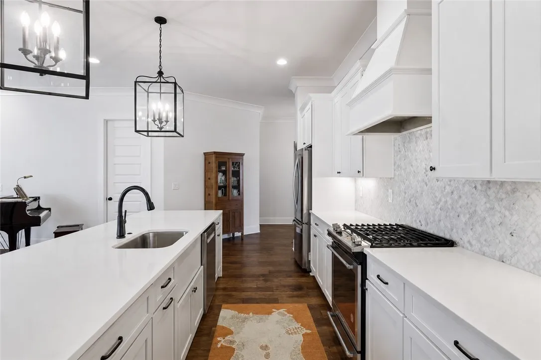 The kitchen's white cabinetry and countertops are balanced by the warm wood floors.