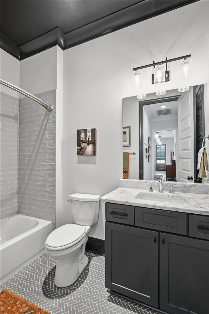 A striking herringbone floor, marble countertops, classic subway tile surround, and a dark ceiling create depth and distinction in this guest bath.
