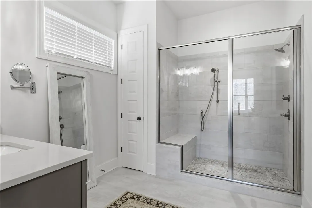 The oversized shower features two showerheads, and the adjacent linen closet offers ample storage, including space for a laundry basket.