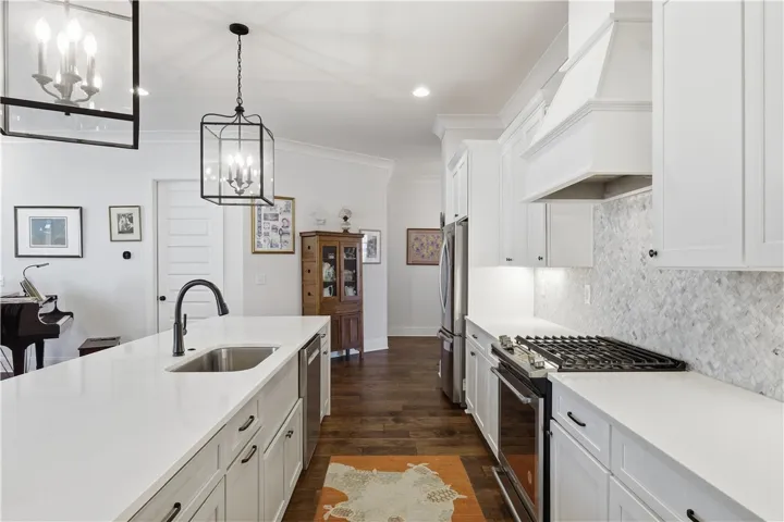 The well-appointed kitchen offers a beautiful marble backsplash, expansive prep surfaces, a gas range, and an open, light-filled layout.
