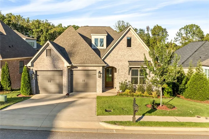 A classic brick exterior meets multiple gables and a concrete driveway leading to the garage.