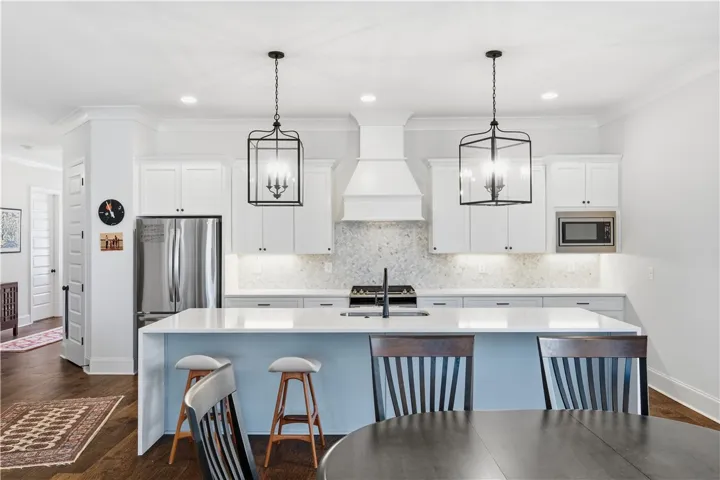 The substantial kitchen island makes a statement with its quartz waterfall edge and generous seating capacity.