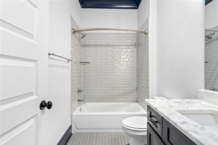 A striking herringbone floor, marble countertops, classic subway tile surround, and a dark ceiling create depth and distinction in this guest bath.