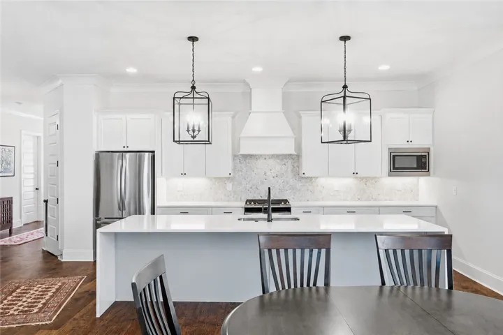 The substantial kitchen island makes a statement with its quartz waterfall edge and generous seating capacity.