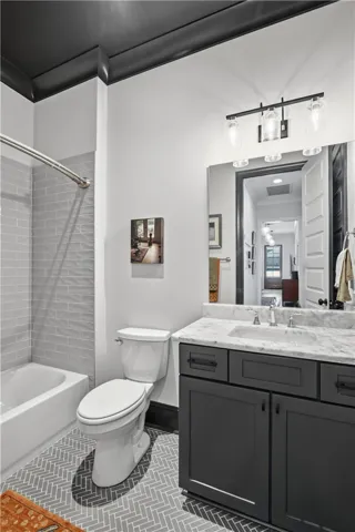 A striking herringbone floor, marble countertops, classic subway tile surround, and a dark ceiling create depth and distinction in this guest bath.