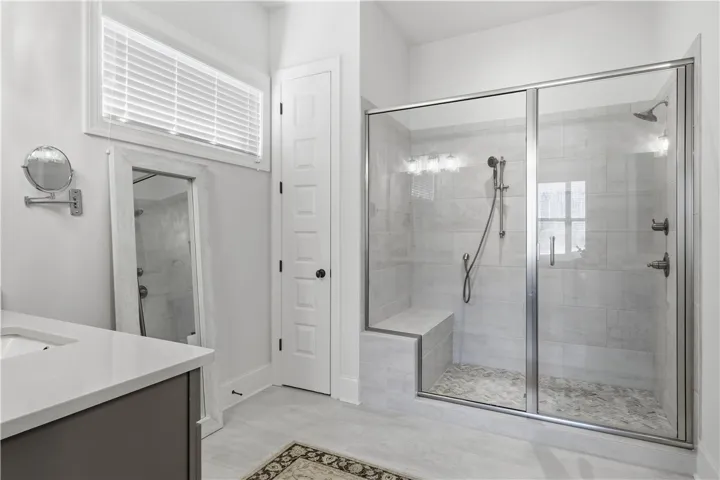 The oversized shower features two showerheads, and the adjacent linen closet offers ample storage, including space for a laundry basket.