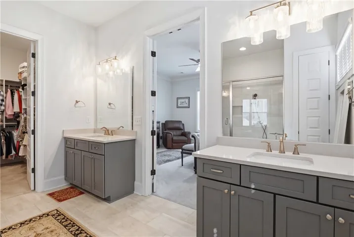Accessed through double doors, the generously sized primary bath features dual quartz-topped vanities, a tile step-in shower with bench, a private water closet, and a dedicated linen closet.