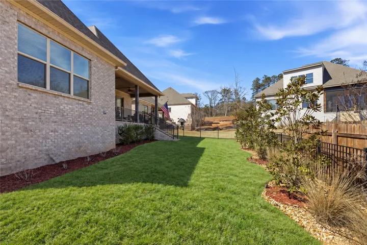 The wide rear yard provides generous space for recreation and outdoor enjoyment.red grassy yard is enclosed by secure fencing alongside a classic brick exterior.