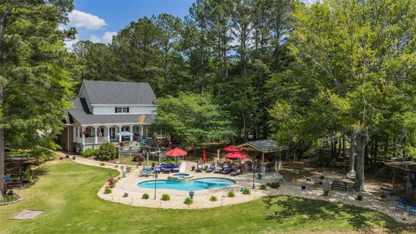 This expansive backyard retreat features a refreshing pool, ample deck space, and lush surrounding trees.