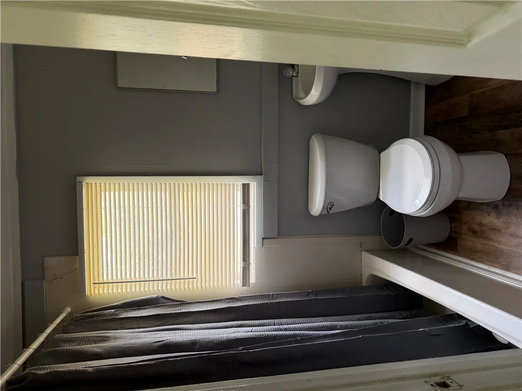 A compact and functional bathroom offering essential amenities with a wood-look floor.