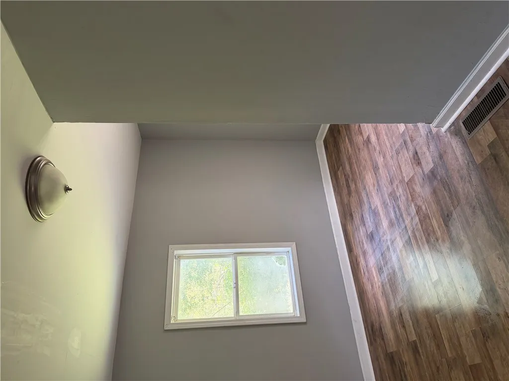 Natural light illuminates rich hardwood flooring within this well-appointed interior space.