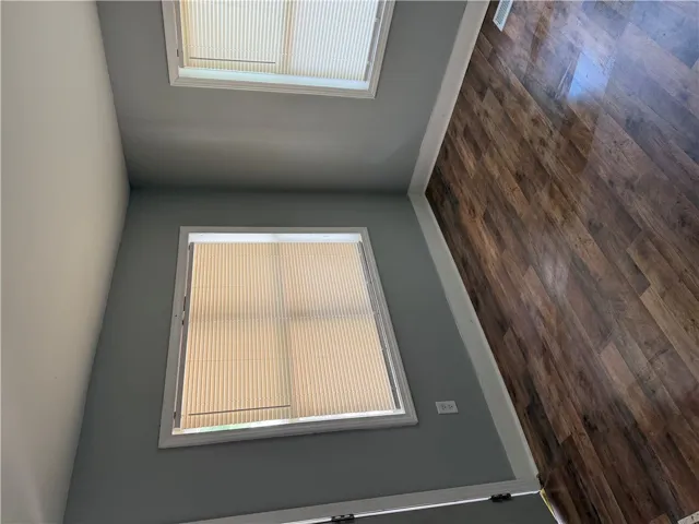 Laminate flooring adds warmth to this versatile interior space, illuminated by multiple windows.