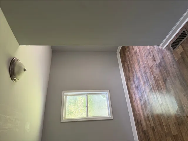 Natural light illuminates rich hardwood flooring within this well-appointed interior space.