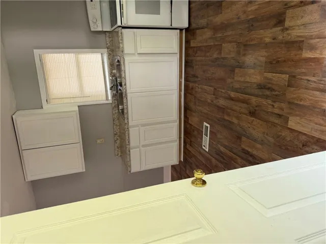 A well-appointed kitchen features ample white cabinetry, granite counters, and wood-look flooring.