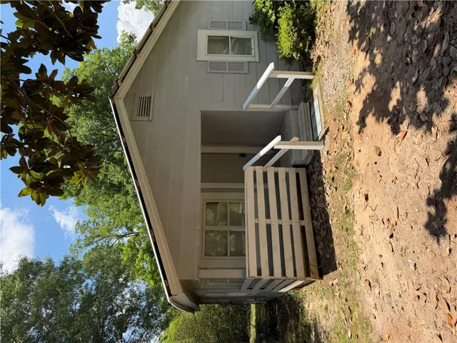 A charming single-story residence with a welcoming front porch, nestled amidst mature trees.