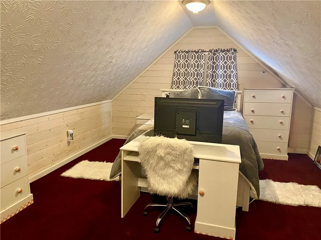 Slanted ceilings and shiplap paneling create a cozy bedroom retreat or bonus room.
