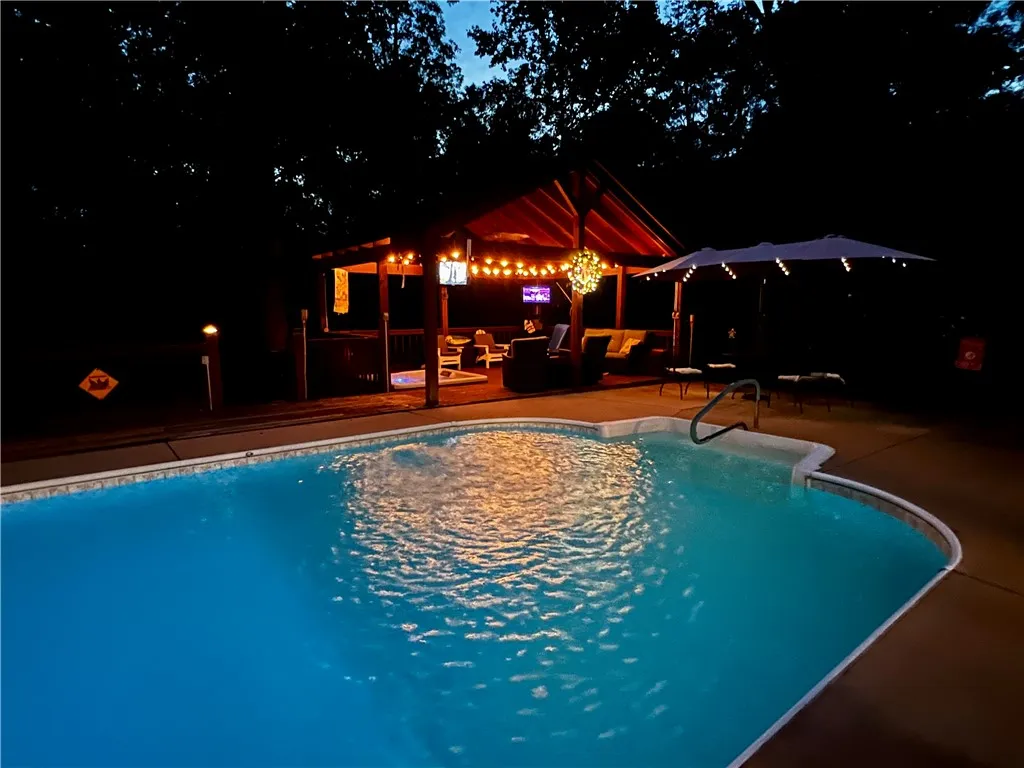An inviting backyard oasis offers a sparkling pool and a covered outdoor lounge, perfect for evening entertaining.