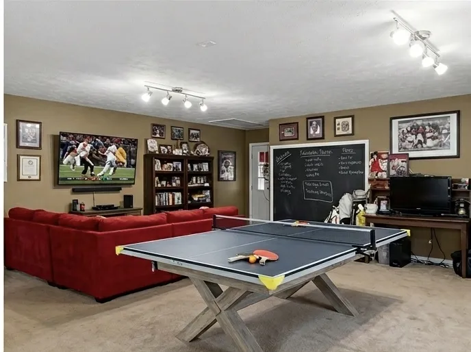 A versatile recreation room boasts track lighting, a comfortable seating area, and a large chalkboard wall for creative expression.
Note: Photo has been digitally altered to showcase different furniture arrangement.